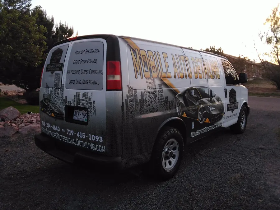 The back of the Medina Brothers van listing headlight restoration, engine steam cleaning, wax polishing, carpet extraction and odor removal